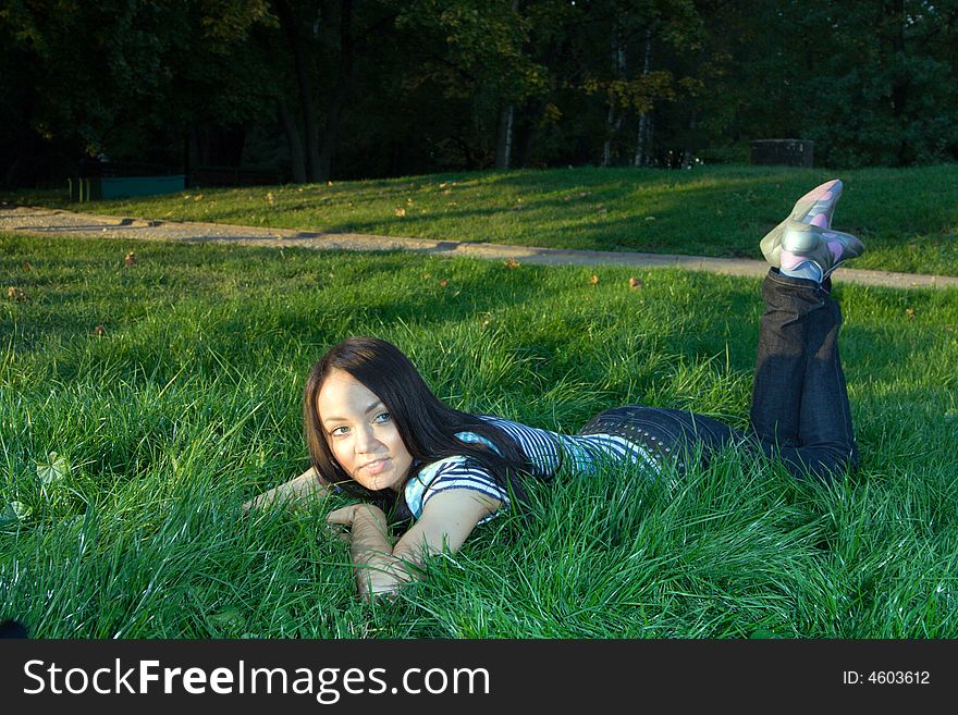 Young beautiful dark-haired woman lying at grass and smiling. Young beautiful dark-haired woman lying at grass and smiling