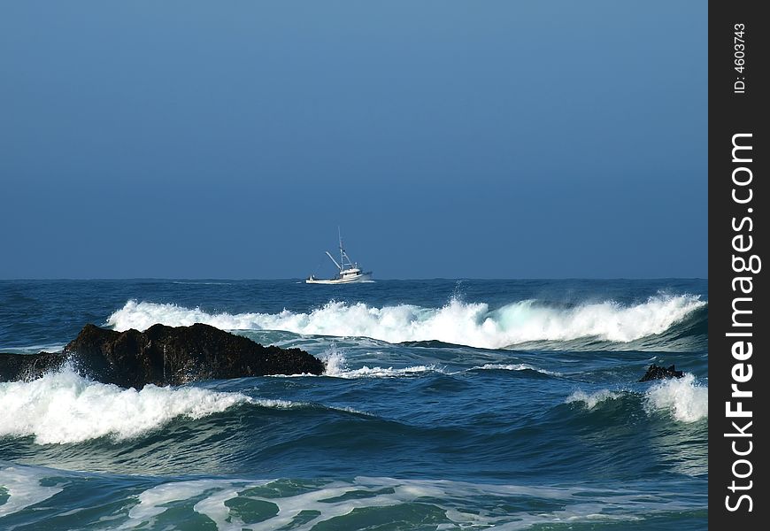 Fishing trawler heading out with ocean waves in foreground. Fishing trawler heading out with ocean waves in foreground