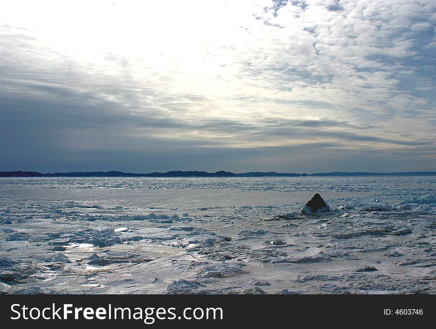 A frozen seascape of the north Atlantic with a lonely rock and cloudy sky overhead