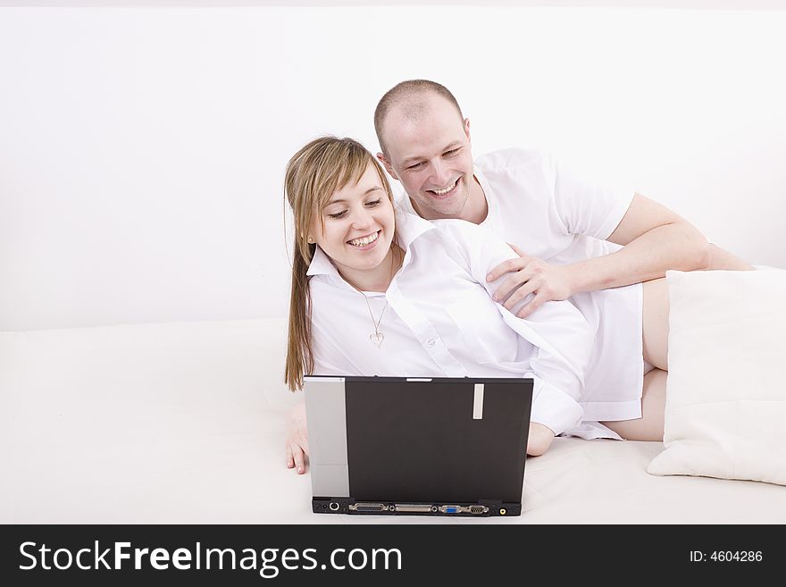 Happy couple with laptop on a couch. Relax at home.