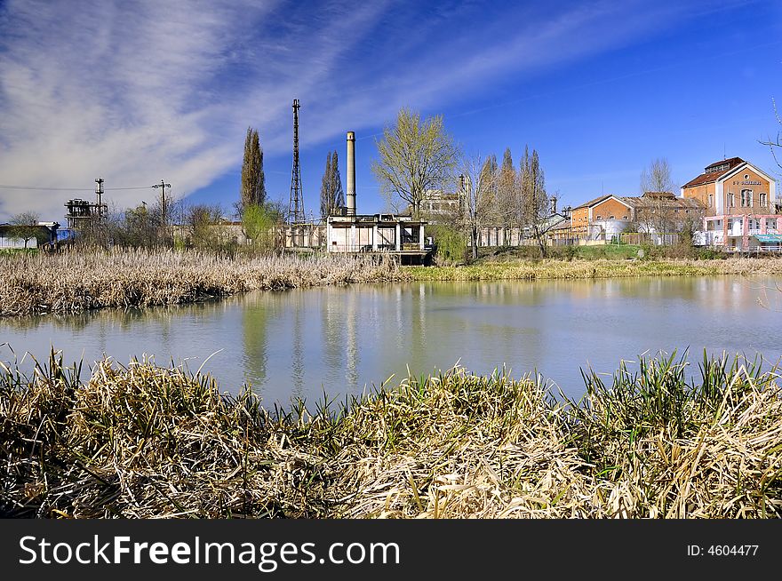 A view with an abandoned industrial facility and water reflection