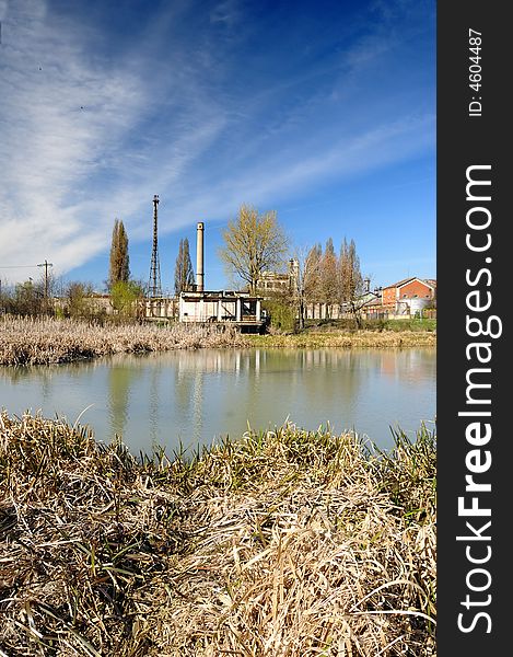 A view with an abandoned industrial facility and water reflection