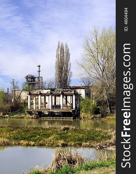 A view with an abandoned industrial facility and water reflection