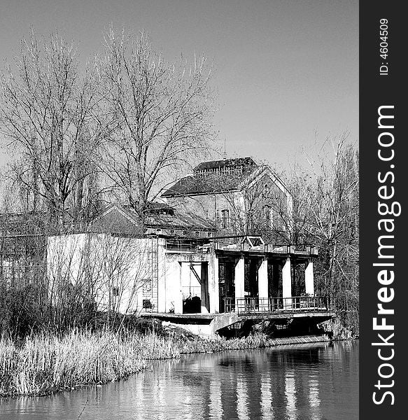 A view with an abandoned industrial facility and water reflection