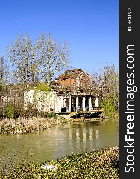 A view with an abandoned industrial facility and water reflection