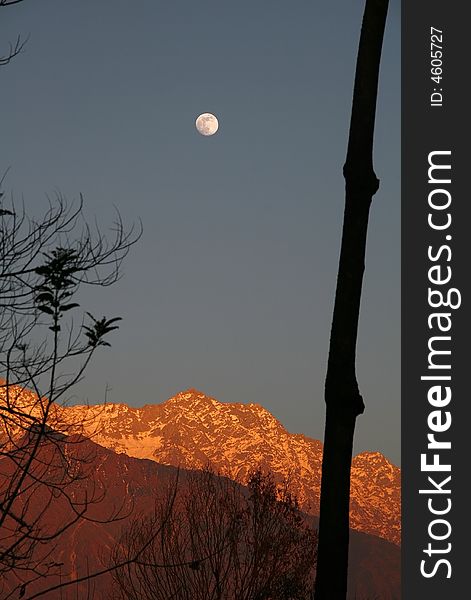 Fullmoon rise  and vivid sunset on snowpeaked   In