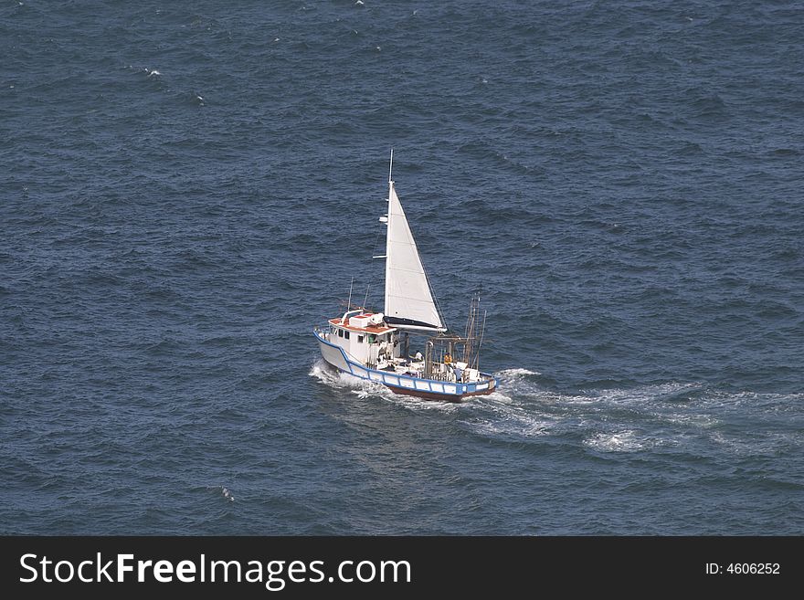 A fishing boat heads out to sea under sail from Hout Bay. A fishing boat heads out to sea under sail from Hout Bay