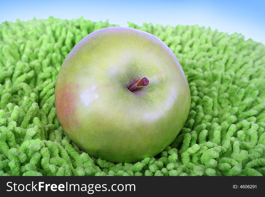 Green juicy apple on the artificial grass