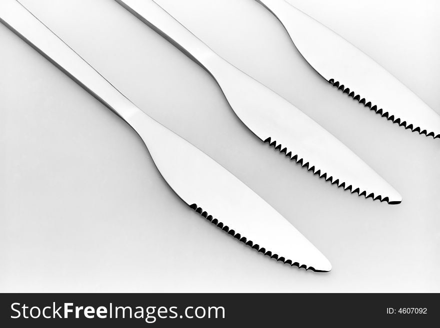 Three knives on a grey background