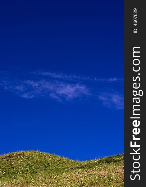 Green hill on blue sky with small cloud traces. Green hill on blue sky with small cloud traces