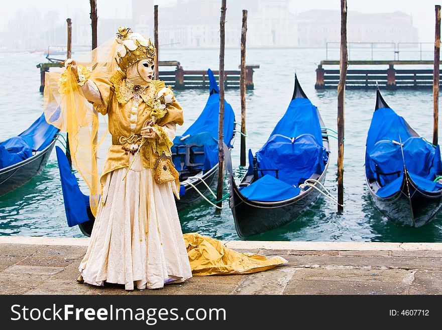 A lady wearing a wonderful gold costume in front of gondolas. A lady wearing a wonderful gold costume in front of gondolas