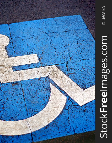 International symbol for handicapped parking, blue paint on asphalt. International symbol for handicapped parking, blue paint on asphalt