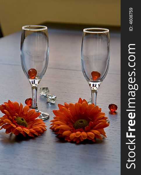 Two Wine-glass on a table near to a flowers.