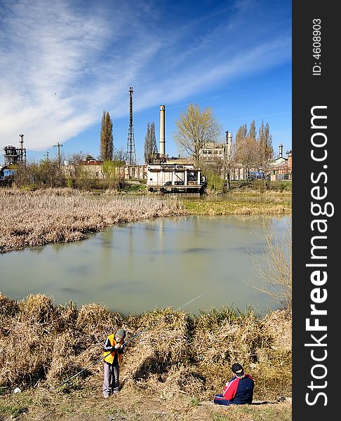 Little boy fishing in an industrial waste waters.