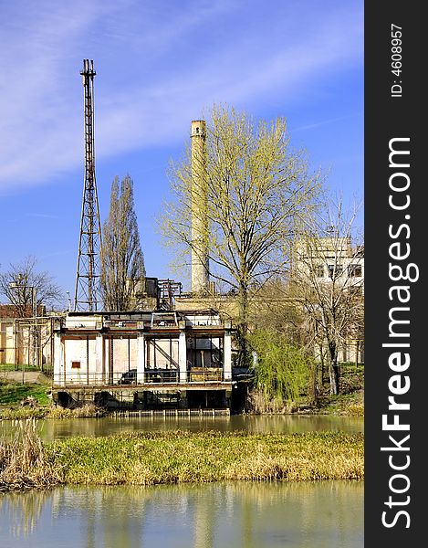 A view with an abandoned industrial facility and water reflection