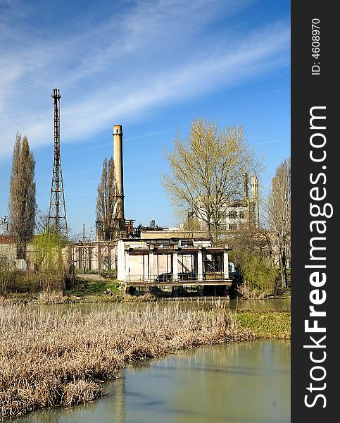 A view with an abandoned industrial facility and water reflection