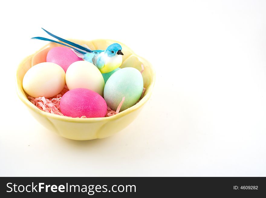 Hardboiled and dyed Easter eggs in a bowl with a decorative blue bird sitting to one side. Hardboiled and dyed Easter eggs in a bowl with a decorative blue bird sitting to one side.