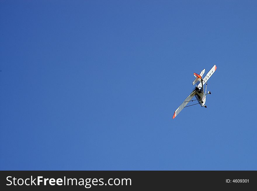 Sports ultralight airplane in turn left in the blue sky. Sports ultralight airplane in turn left in the blue sky