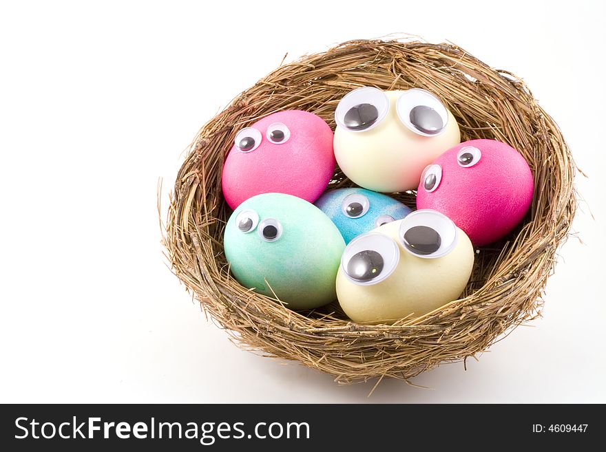 A simple shot of six dyed Easter eggs with googly eyes snuggled into a birds nest. A simple shot of six dyed Easter eggs with googly eyes snuggled into a birds nest.