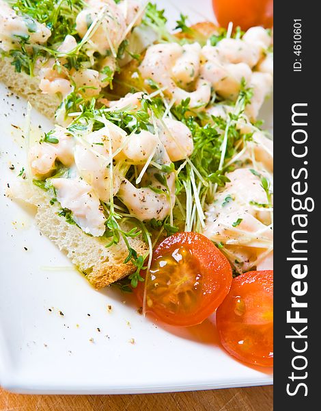 Sliced prawn and cress sandwich with tomatoes on a white plate