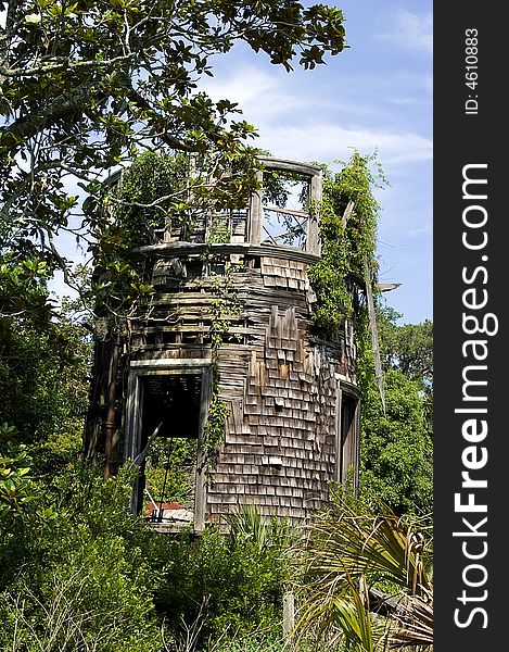 A round shingled tower on Cumberland Island,GA, is in a dilapidated condition. Foliage abounds as nature is reclaiming it. A round shingled tower on Cumberland Island,GA, is in a dilapidated condition. Foliage abounds as nature is reclaiming it.