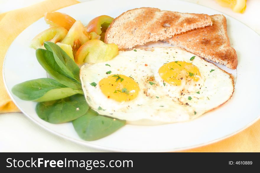 Two sunny side up eggs on plate with fresh vegetables and wholewheat toast. Two sunny side up eggs on plate with fresh vegetables and wholewheat toast
