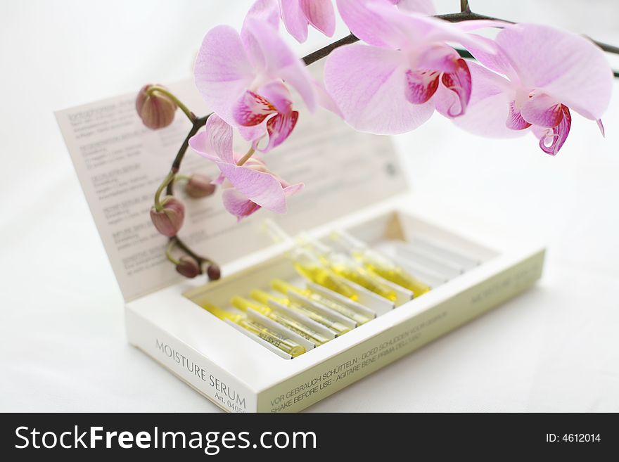 Serum Ampules in the box with pink orchid around. Serum Ampules in the box with pink orchid around