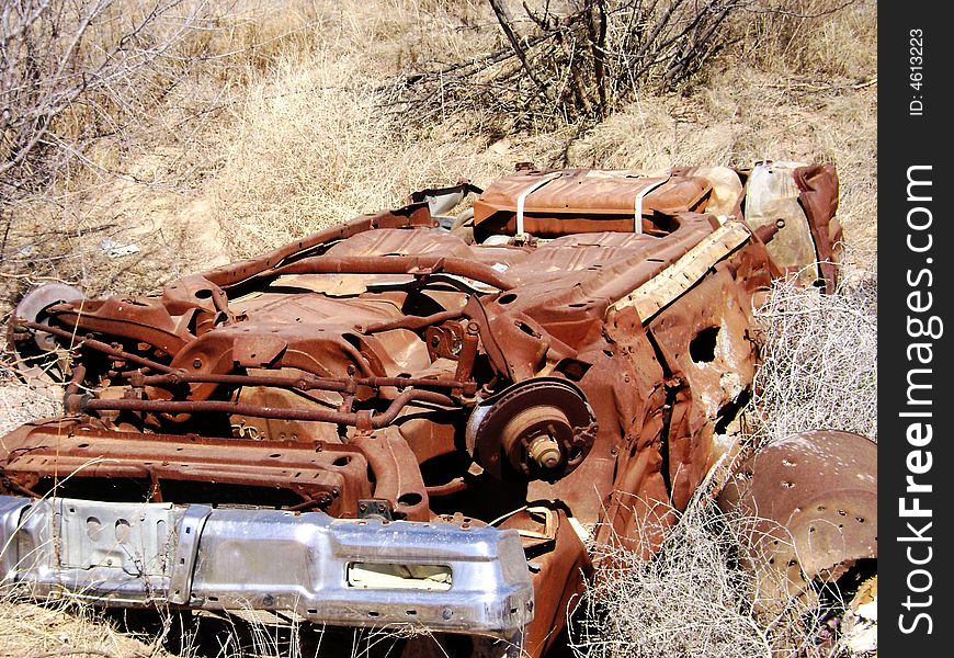 Old rusted car laying upside down in a ditch.