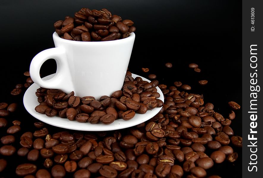 White coffee cup full of coffee beans on a black background. White coffee cup full of coffee beans on a black background