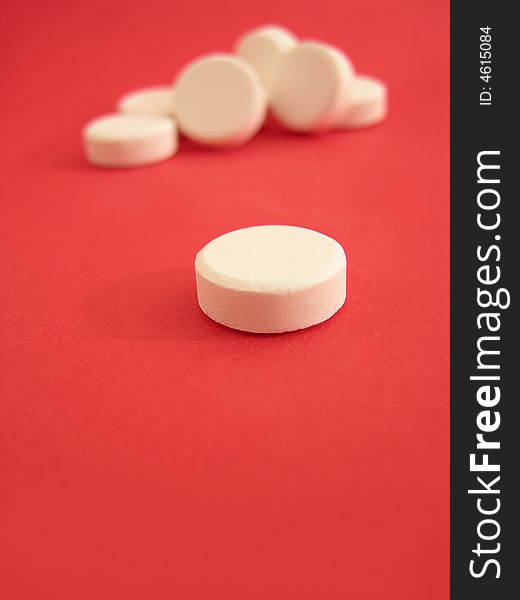 White tablets on the red background.
Focus on the first plane