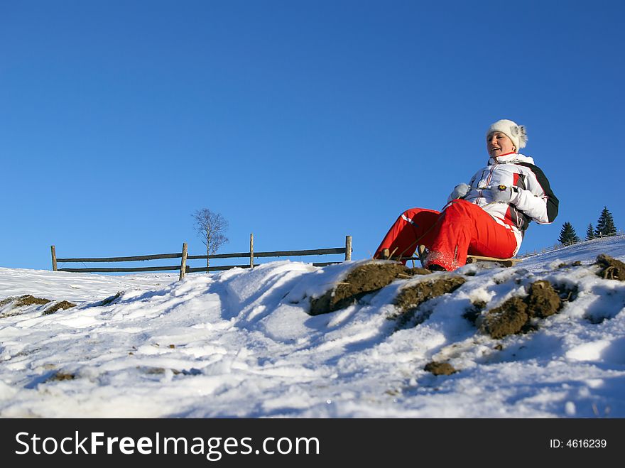 The sports girl on sledge climbs down a mountain