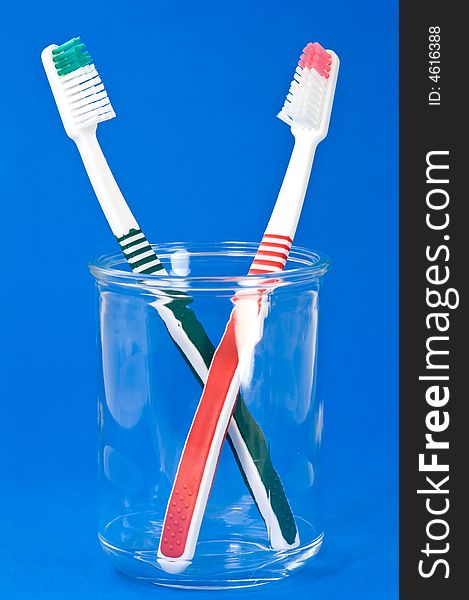 Two toothbrushes in glass on blue textured background. Two toothbrushes in glass on blue textured background