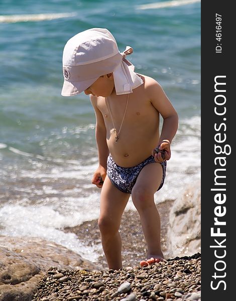 A little boy plays at a large stone ashore black sea. A little boy plays at a large stone ashore black sea