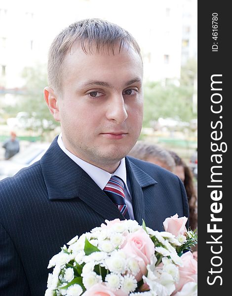Well-dressed groom with a rose bouquet. Well-dressed groom with a rose bouquet