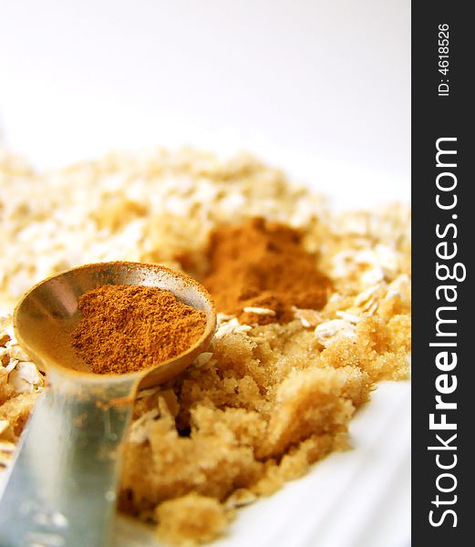 Image of cinnamon in a metal measuring spoon, with brown sugar and oats.  Room for text or other material remains at the top of the image. Vertical orientation. Image of cinnamon in a metal measuring spoon, with brown sugar and oats.  Room for text or other material remains at the top of the image. Vertical orientation.