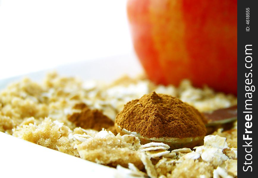 Image of a heaping spoonful of cinnamon, with brown sugar and oats surrounding and a bright red apple in the backgroujnd.  Room for text remains in top left hand quarter of the image.  Horizontal orientation. Image of a heaping spoonful of cinnamon, with brown sugar and oats surrounding and a bright red apple in the backgroujnd.  Room for text remains in top left hand quarter of the image.  Horizontal orientation.