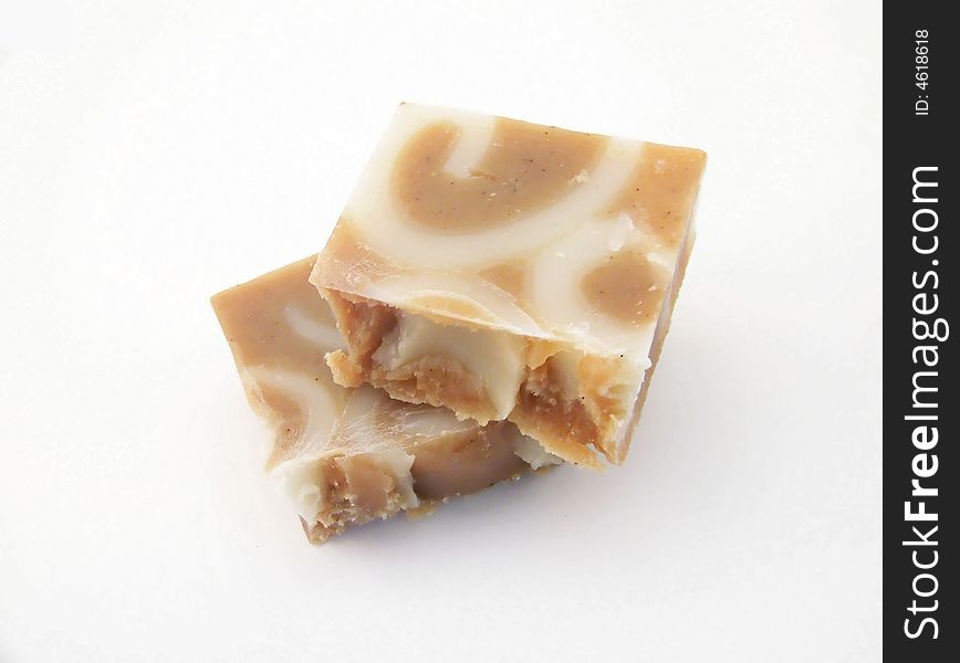 A bar of homemade, handcut cinnamon soap broken into two pieces, on a white background.  Horizontal orientation. A bar of homemade, handcut cinnamon soap broken into two pieces, on a white background.  Horizontal orientation.