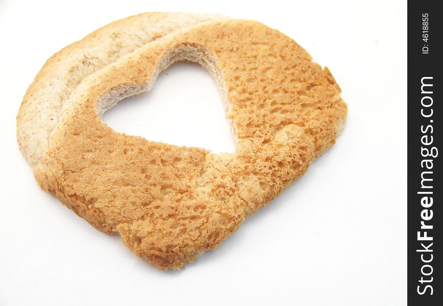Image of a slice of wheat bread with a heart cut out, placede at an angle.  White background, horizontal orientation. Image of a slice of wheat bread with a heart cut out, placede at an angle.  White background, horizontal orientation.