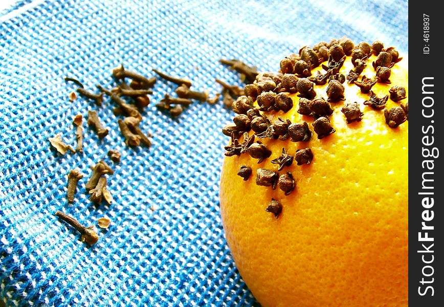 Image of a bright orange with cloves on a bright blue cloth.  Horizontal orientation. Image of a bright orange with cloves on a bright blue cloth.  Horizontal orientation.