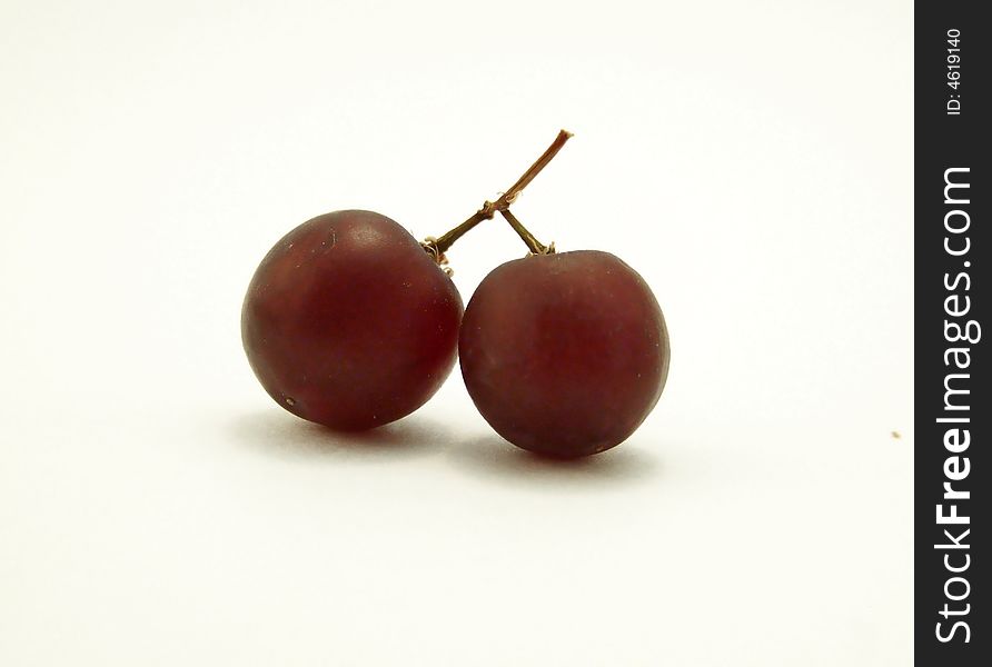 Close up image of two red grapes joined together, resembling cherries, centered in frame.  White background and horizontal orientation. Close up image of two red grapes joined together, resembling cherries, centered in frame.  White background and horizontal orientation.