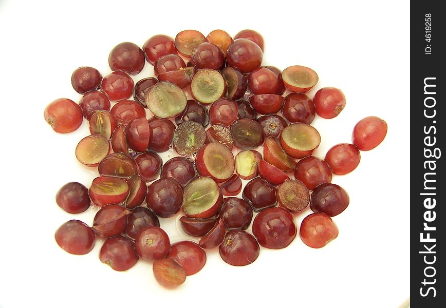 Image of sliced red grapes that have been placed in water, on white.  Horizontal orientation. Image of sliced red grapes that have been placed in water, on white.  Horizontal orientation.