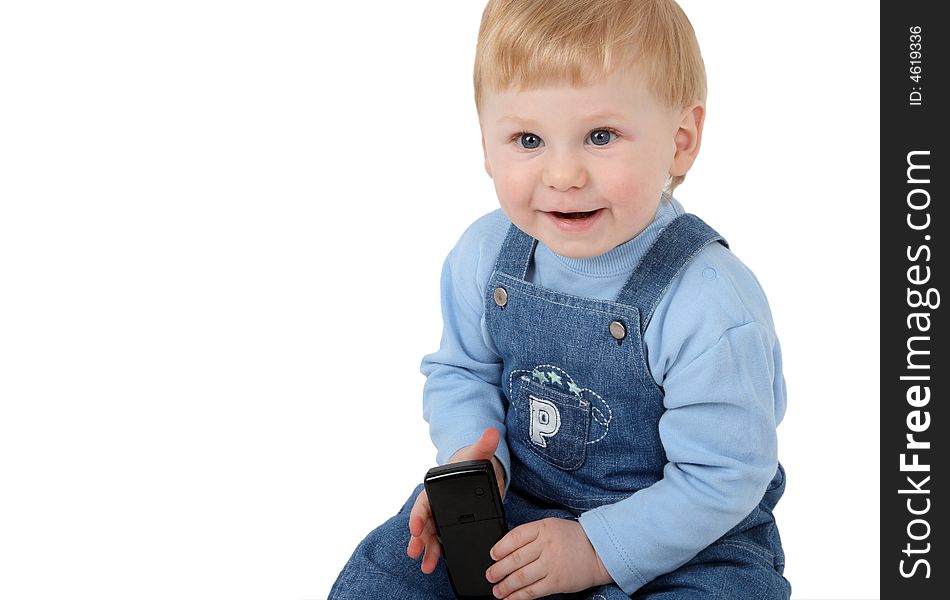 The small beautiful boy laughs and sits at a mobile phone in hands. The small beautiful boy laughs and sits at a mobile phone in hands