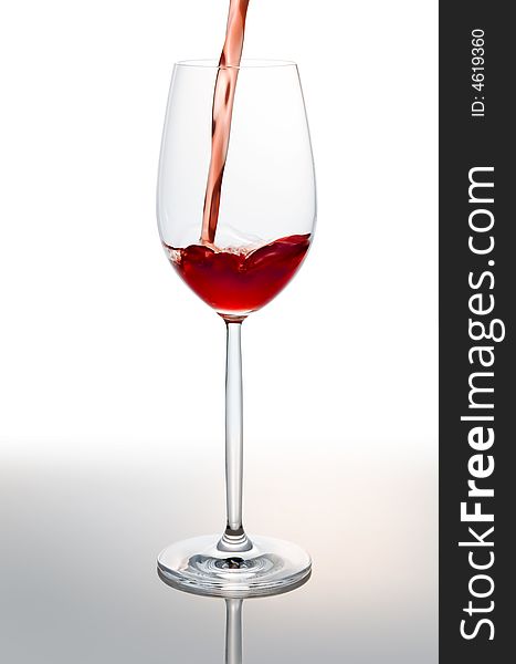 Pouring red wine into glass over a mirror