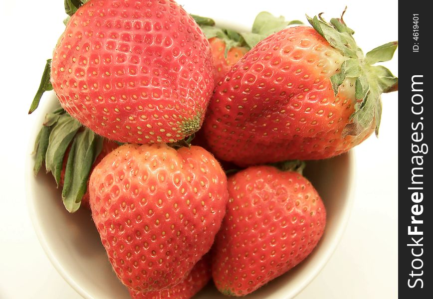 Close up image of a small white bowl with four large bright red strawberries, on white background. Close up image of a small white bowl with four large bright red strawberries, on white background.