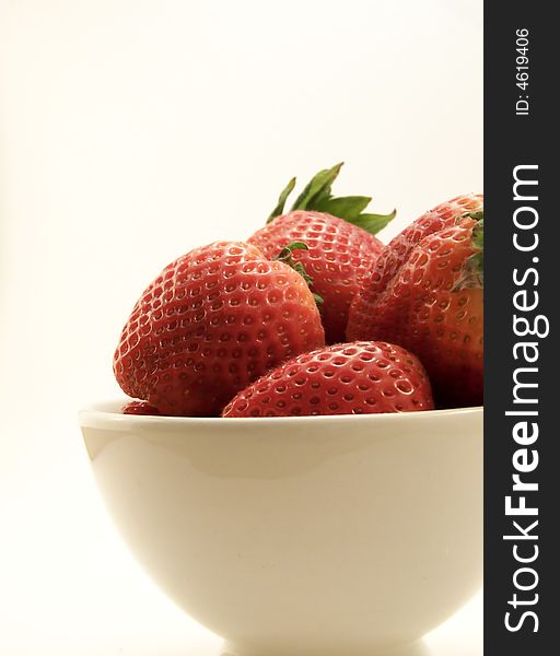 Close up image of four large red strawberries in a small white bowl, on white background. Close up image of four large red strawberries in a small white bowl, on white background.