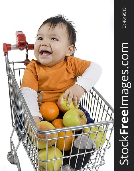 Baby sitting in a shopping cart with fruit before white 
background. Baby sitting in a shopping cart with fruit before white 
background
