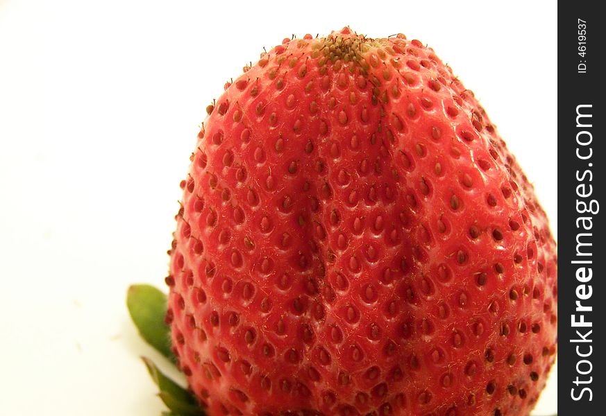 Close up image of an large, bright red strawberry, turned upside down.  Room for text or other material remains at left of image.  White background and horizontal orientation. Close up image of an large, bright red strawberry, turned upside down.  Room for text or other material remains at left of image.  White background and horizontal orientation.