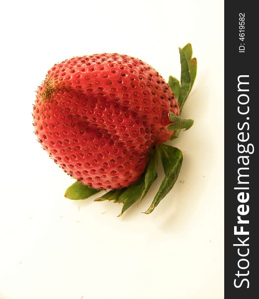 Image of a large, bright red strawberry turned upside down.  Angled shot with vertical orientation and white background. Image of a large, bright red strawberry turned upside down.  Angled shot with vertical orientation and white background.