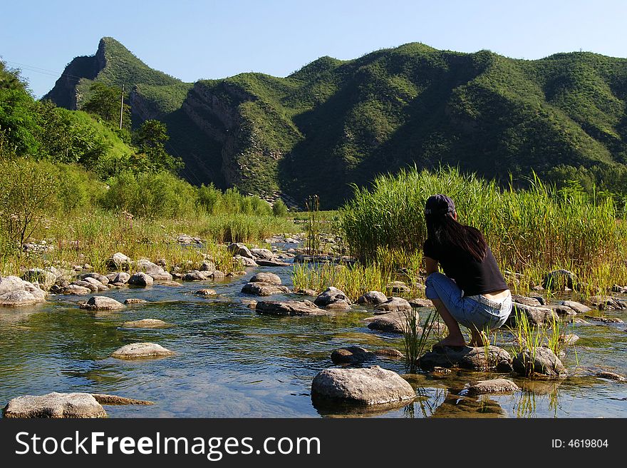 A limpid river running through the mountains,there is a beauty sitting by the water. A limpid river running through the mountains,there is a beauty sitting by the water