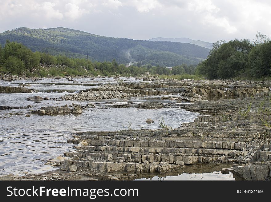 The mountain river flowing on stones with mountains on a background